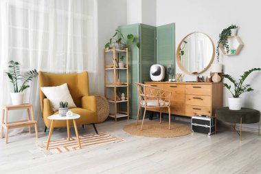 Çekmeceleri, bitkileri ve koltuğu olan makyaj odasının içi.