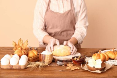 Balkabağı şeklinde çörekler hazırlayan kadın ışık duvarının yanındaki masada.