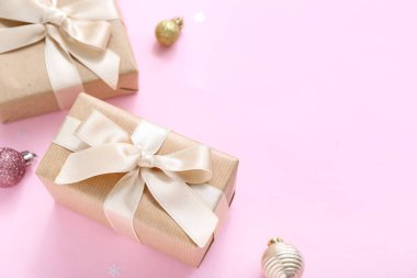 Pembe arka planda Noel baloları ve hediye kutuları