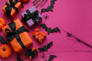 Mor arka planda Cadılar Bayramı için hediye kutuları, balkabakları ve kağıt yarasalarla kompozisyon