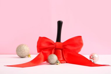 Kırmızı kurdeleli Noel çanı ve renkli arkaplanda toplar
