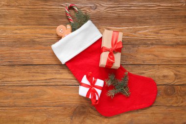 Noel çorabı, köknar dalları, zencefilli ekmek, şeker kamışı ve tahta arka planda hediye kutuları