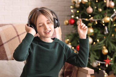 Kulaklıklı şirin bir çocuk Noel arifesinde evde müzik dinliyor.