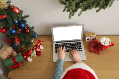 Noel arifesinde ofiste dizüstü bilgisayarla çalışan bir kadın.