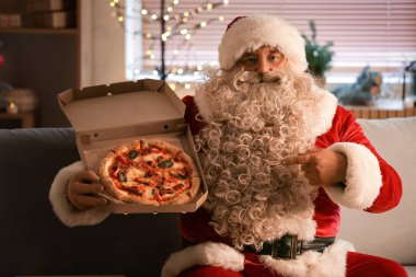 Noel arifesinde evde oturan lezzetli pizzalı Noel Baba