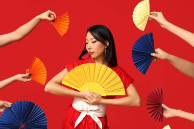 Güzel genç Asyalı kadın ve elleri ve kırmızı arka planda bir sürü hayranı var. Çin Yeni Yıl Kutlaması