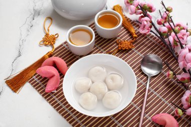 Bambu hasırı, bir kase tangyuan çay, fal kurabiyesi ve beyaz mermer arka planda sakura. Dongzhi Festivali