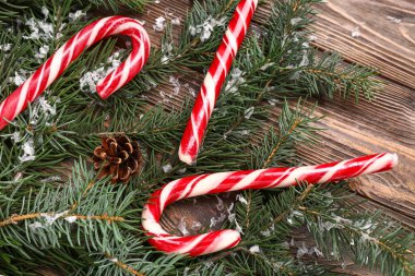 Köknar dallı Noel şekerleri ve tahta arka planda çam kozalakları.