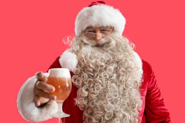 Kırmızı arka planda bir bardak birayla Noel Baba