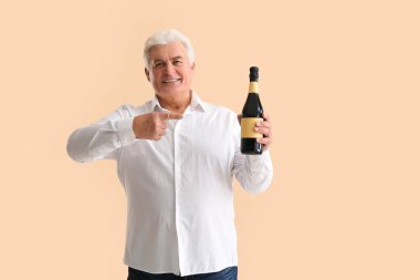 Bir şişe şampanyası olan yaşlı adam bej arka planda Noel 'i kutluyor.