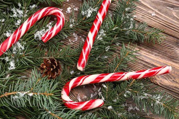 Köknar dallı Noel şekerleri ve tahta arka planda çam kozalakları.