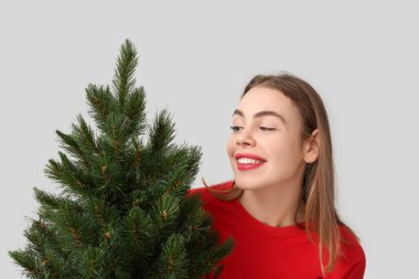 Beyaz arka planda Noel ağacı olan güzel genç bir kadın.