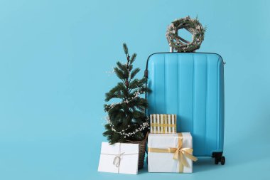 Çelenkli çanta, Noel ağacı ve mavi arka planda hediyeler.