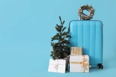 Çelenkli çanta, Noel ağacı ve mavi arka planda hediyeler.