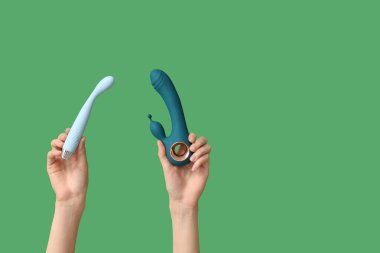 Yeşil arka planda farklı vibratörlere sahip kadın eller.