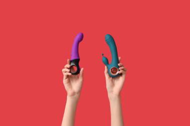 Kırmızı arka planda vibratörlü kadın elleri