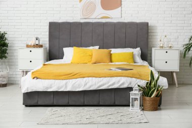 Şık yatak odasının içinde yerde farklı mumlar ve fenerler var.