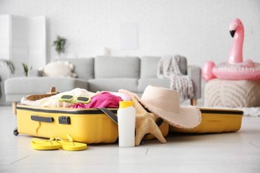 Giysilerin ve plaj aksesuarlarının olduğu bavul oturma odasında. Yaz tatili kavramı