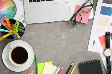 Gri grunge tablosunda dizüstü bilgisayarı, kalemleri ve renk çizelgeleri olan grafik tasarımcılarının çalışma yeri