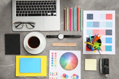 Gri grunge tablosunda dizüstü bilgisayarı, kalemleri ve renk çizelgeleri olan grafik tasarımcılarının çalışma yeri