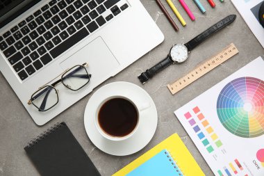 Gri grunge tablosunda dizüstü bilgisayarı, kalemleri ve renk çizelgeleri olan grafik tasarımcılarının çalışma yeri