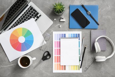 Gri grunge tablosunda dizüstü bilgisayarı, kalemleri ve renk çizelgeleri olan grafik tasarımcılarının çalışma yeri