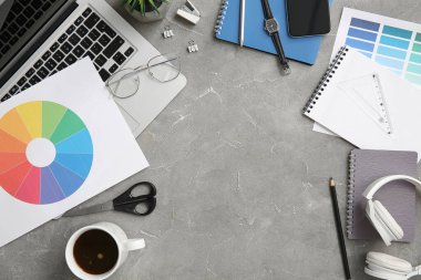 Gri grunge tablosunda dizüstü bilgisayarı, kalemleri ve renk çizelgeleri olan grafik tasarımcılarının çalışma yeri