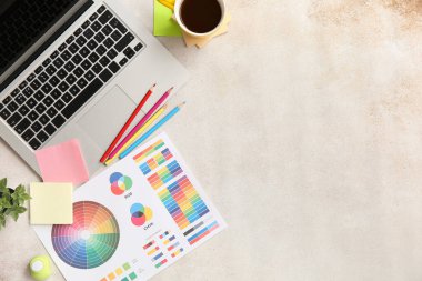 Beyaz grunge masasında dizüstü bilgisayarı, renk çizelgeleri ve kahvesi olan grafik tasarımcılarının çalışma yeri