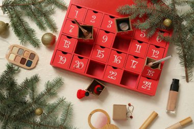 Beyaz arkaplanda Advent takvimi, kozmetik ürünleri ve Noel dekoru