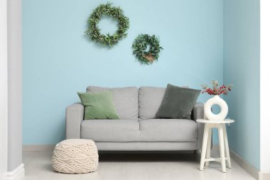 Mavi duvarın yanında kanepesi, masası ve Noel dekoru olan bir oturma odası.