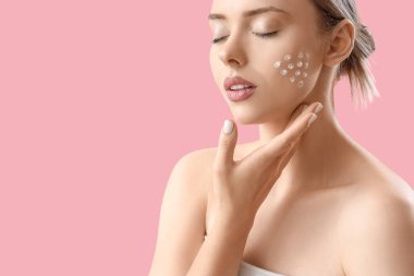 Pembe arka planda krem sürmüş güzel bir genç kadın.