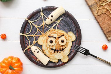 Lezzetli Cadılar Bayramı kahvaltısı ve hafif ahşap arka planda süslemeleri olan kompozisyon