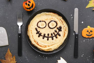 Komik Cadılar Bayramı krepleri, çatal bıçak takımı ve koyu arkaplanda süslemeleri olan kompozisyon