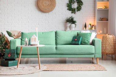 İçinde yeşil kanepe, Noel süsü ve hediyeler olan oturma odası.