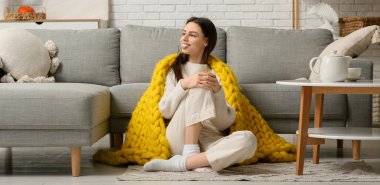 Sıcak sarı ekoseli güzel bir kadın oturma odasında yerde oturuyor.