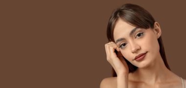 Kahverengi arka planda güzel kaşları olan genç bir kadın ve metin için yeri var.