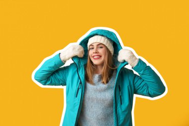 Sarı arka planda sıcak kış giysileri içinde güzel, genç ve mutlu bir kadın.