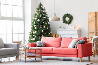 Noel ağacı ve pembe kanepeli şenlikli bir oturma odası.