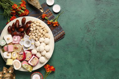 Mumlu Diya lambaları, kadife çiçekleri ve grunge yeşil arka planda farklı ikramlar. Divaly kutlaması