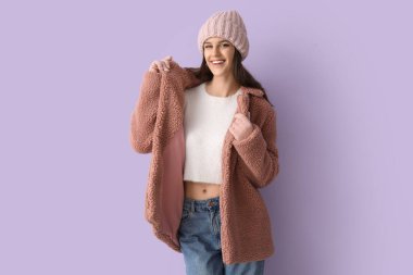 Leylak arkaplanda oyuncak ceketli genç bir kadın.