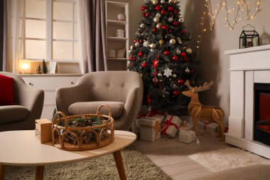 Oturma odasının içinde Noel ağacı, şömine ve koltuklar var.