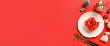 Noel yemeği için güzel bir masa. Hediye ve kırmızı arka planda süslemeler. Mesaj için yer var.