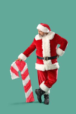 Yeşil arka planda şeker kamışı şeklinde pinyatası olan Noel Baba.