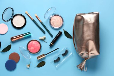 Makyaj ürünleri ve mavi arka planda güzel çiçeklerle süslü bir makyaj çantası.