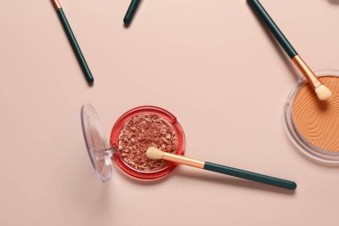 Pembe arka planda makyaj fırçaları ve farklı dekoratif kozmetikler