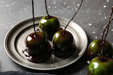 Siyah arka planda Cadılar Bayramı için lezzetli karamelli elma tabağı.