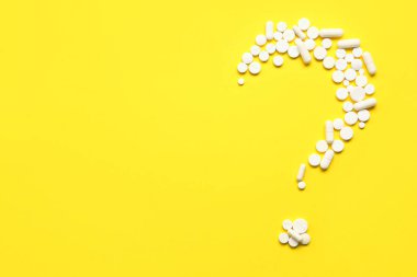 Sarı arka planda beyaz haplardan oluşan soru işareti