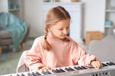 Evde sentezleyici oynayan sevimli küçük kız.