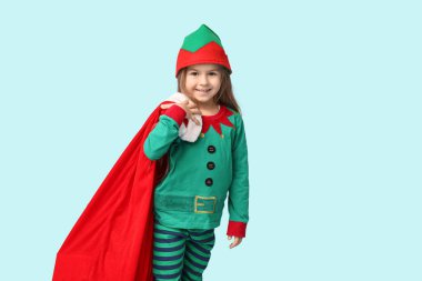 Mavi arka planda hediyeler taşıyan elf kostümlü şirin küçük kız.