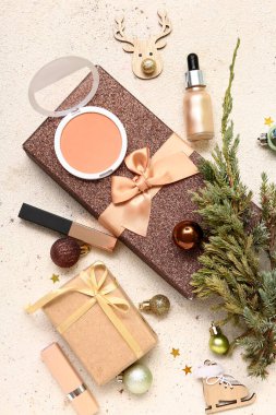 Farklı makyaj ürünleri, hediye kutuları ve arka planda köknar ağacı dalıyla Noel kompozisyonu